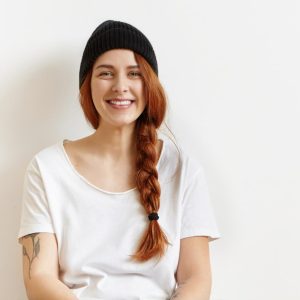 fashionable-young-redhead-woman-with-braid-tattoo-shoulder-having-rest-indoors